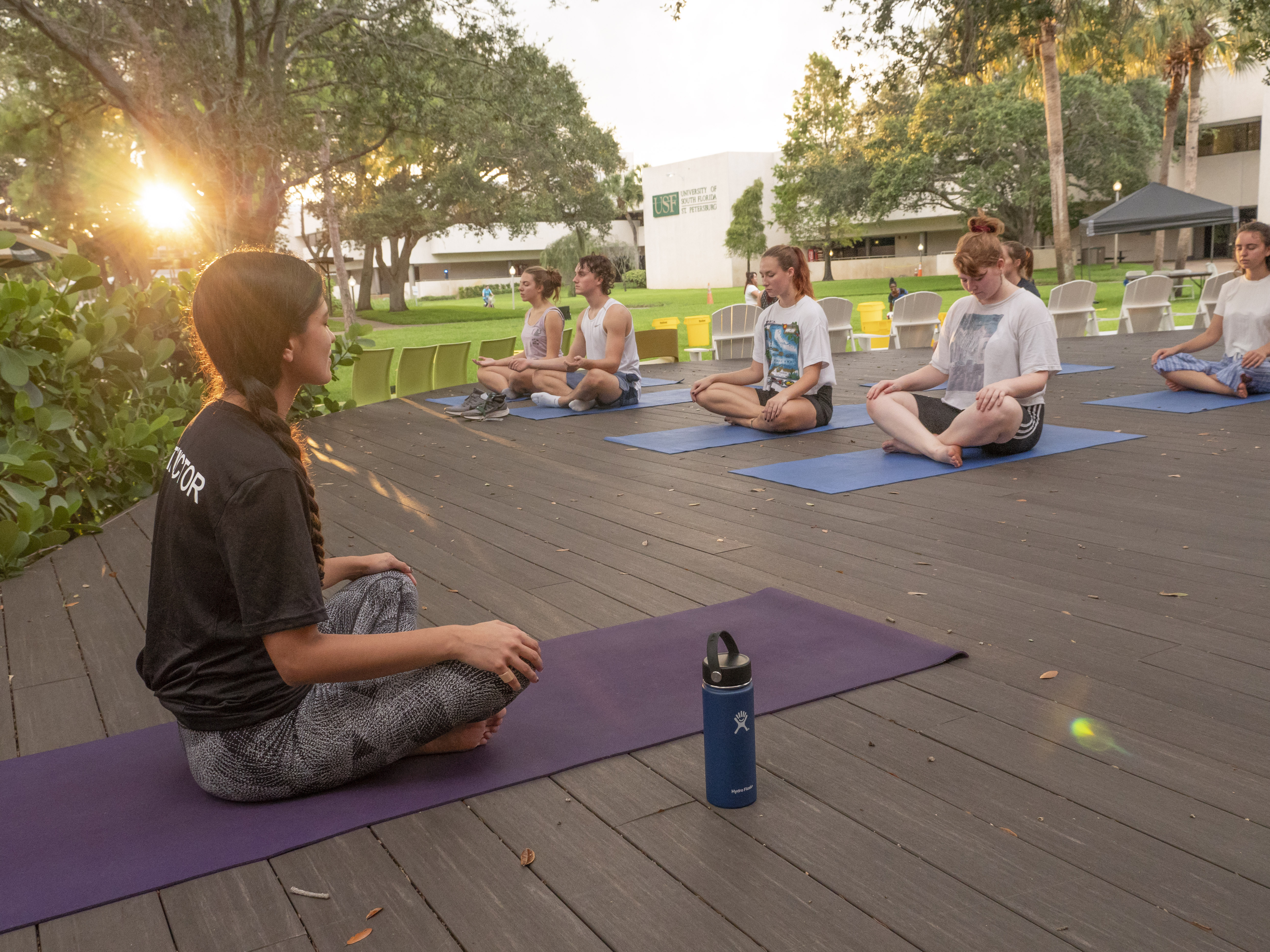 Students sit on the Edge West Deck doing Yoga at sunset