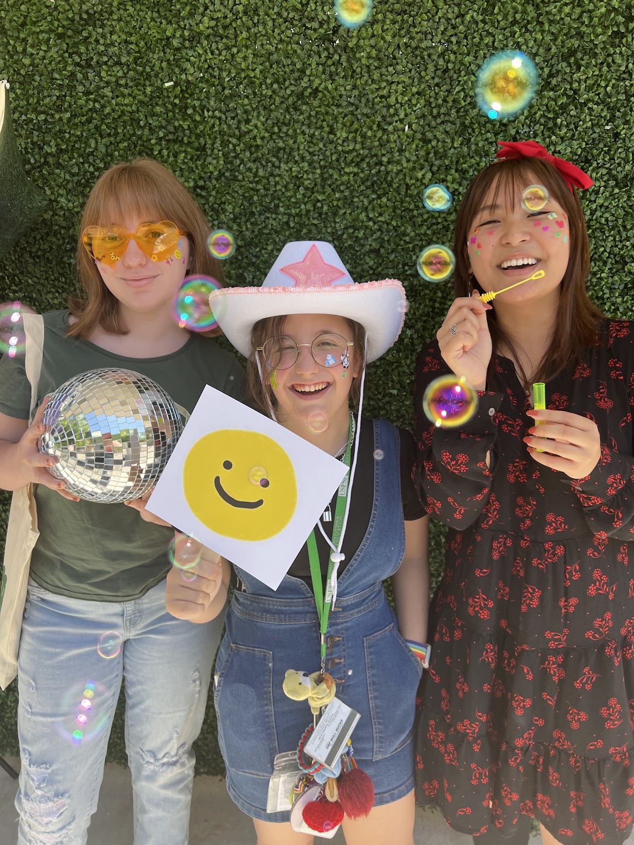 Three students smile with bubbles in the air. 