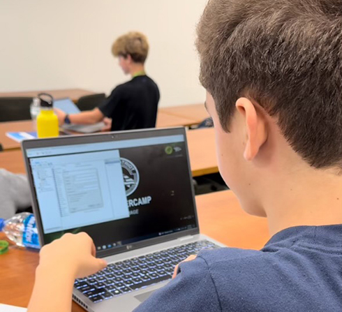 student sitting at desk working on laptop