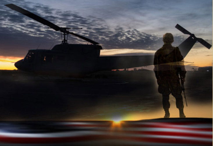 Member of the military in front of a helicopter.