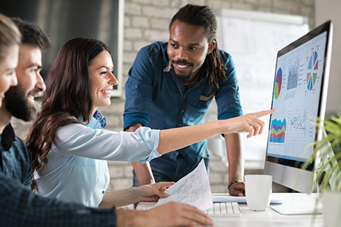 People gathered around a computer monitor working together.