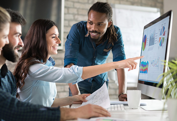 People gathered around a computer monitor working together.