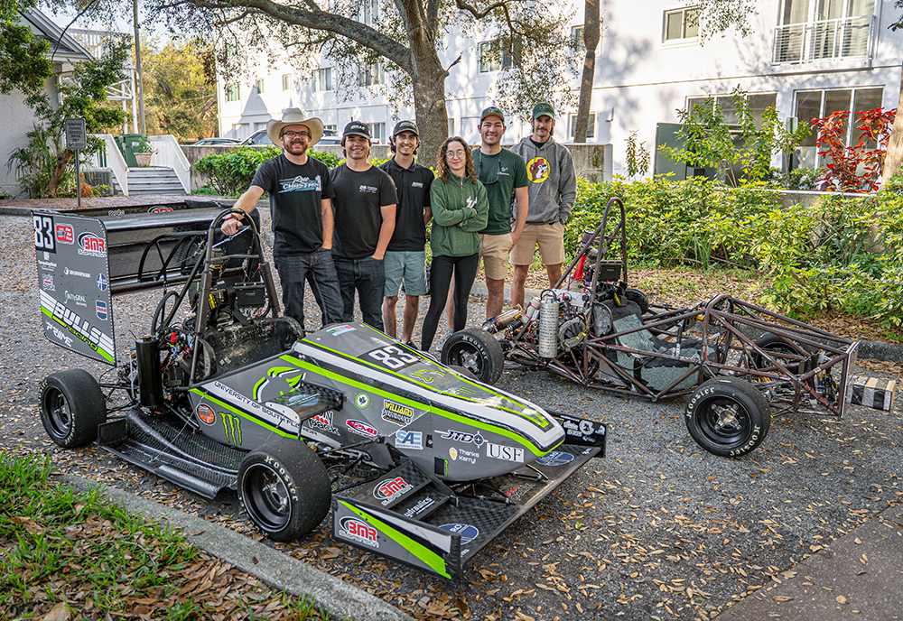 members from the bulls racing team with two of their racing cars
