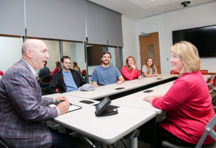 Faculty and students sitting at a table in the Consumer Insight and Sales Lab