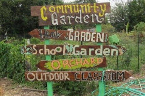 Wooden sign in garden with the words: Community Garden, Herb Garden, School Garden, Orchard, Outdoor Classroom