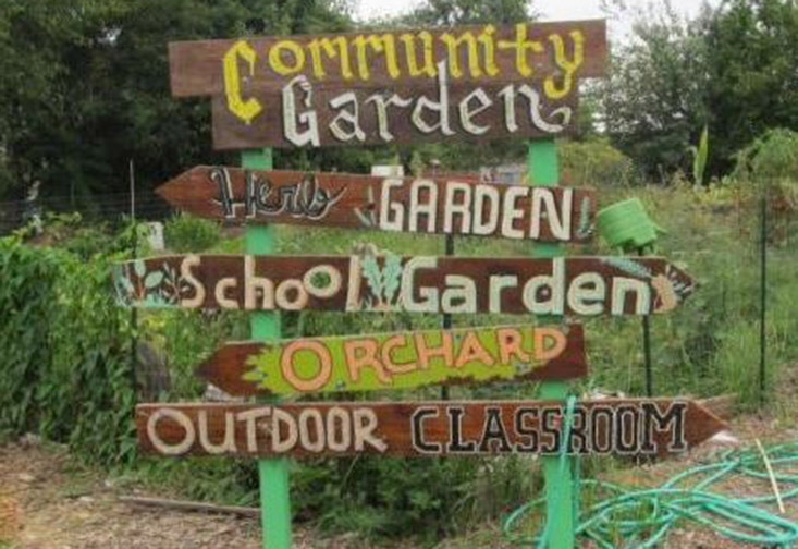Wooden sign in garden with the words: Community Garden, Herb Garden, School Garden, Orchard, Outdoor Classroom