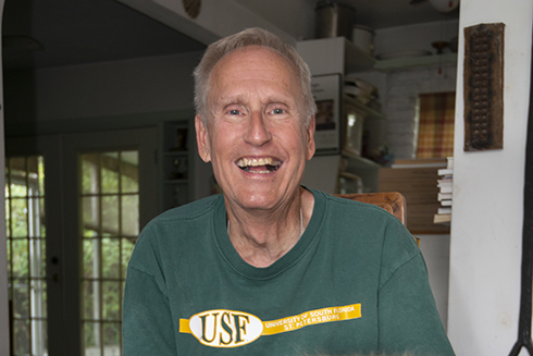 David Connelly wearing a USF shirt sitting next to his dog.