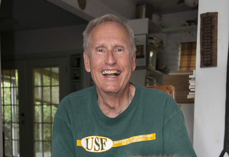 David Connelly wearing a USF shirt sitting next to his dog.