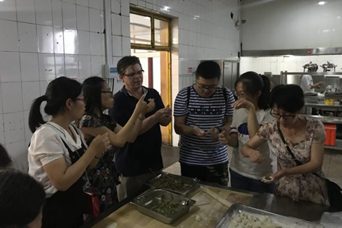 Chemistry Instructor John Osegovic not only taught students, but was taught by them, here learning how to make dumplings.
