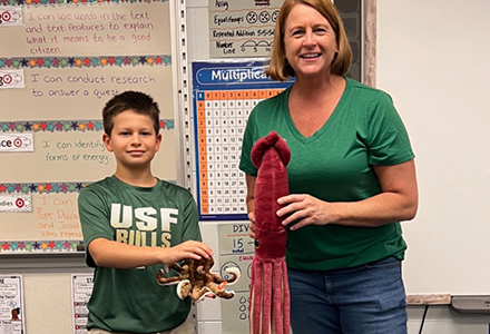 teacher and student each holding a fake octopus