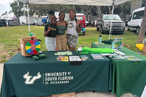 Three female students running the USF St. Petersburg table at the Grand Prix
