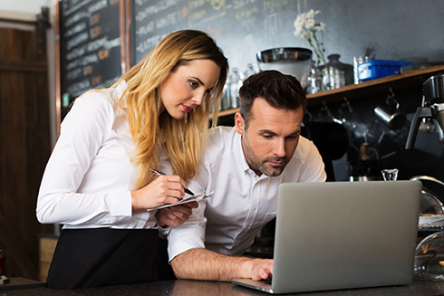 Man and woman working together on laptop in restaurant
