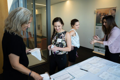 An adult with students at a sign up table for Innovation Scholar activities