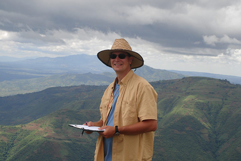 John Arthur on the top of a mountain with a mountain range in the background