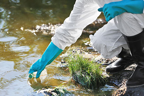 Person wearing gloves getting a water sample.