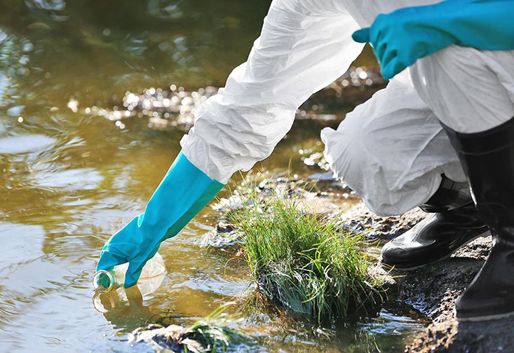 Person wearing gloves getting a water sample.