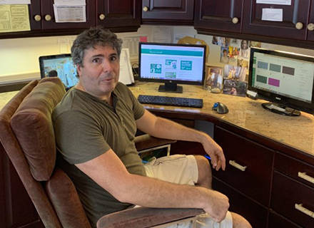 Jude Labarca sitting at home in front of three computer monitors