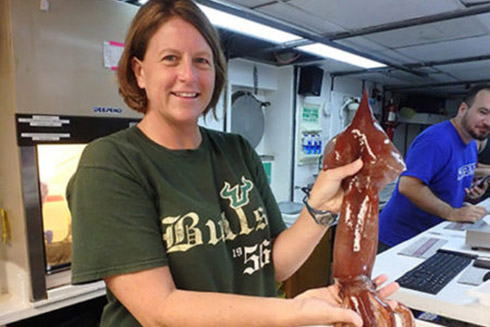 Professor Heather Judkins on board a research vessel in the Gulf of Mexico analyzing a recently captured squid.