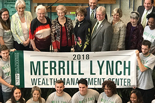 People holding a banner that says 2018 Merrill Lynch Wealth Management Center