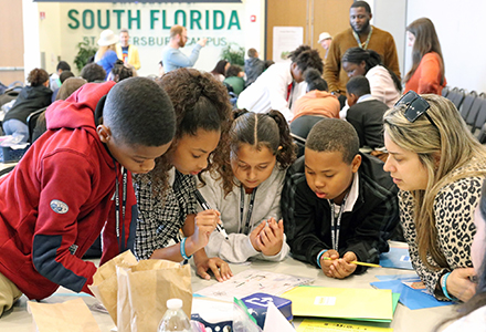 group of kids huddled around a table working on a project