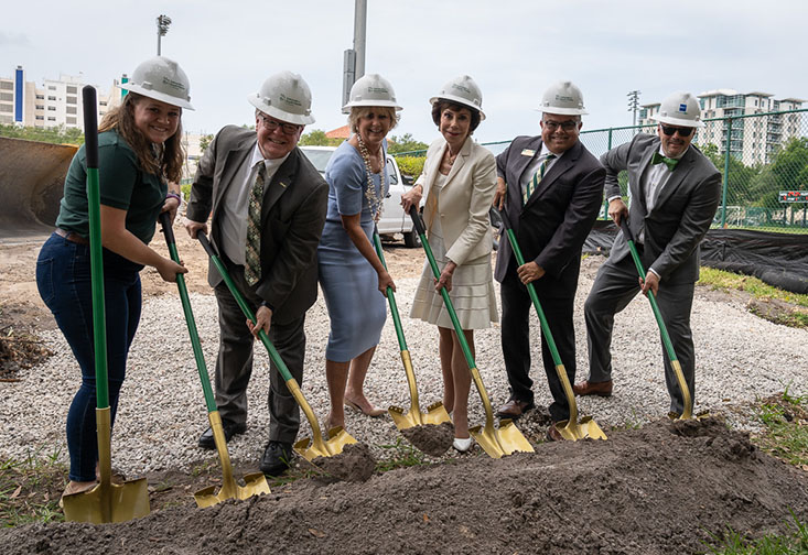 Leadership on the USF St. Petersburg campus wearing hard hats and holding shovels at the groundbreaking ceremony.