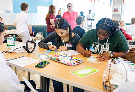 students sitting at a table coloring with markers