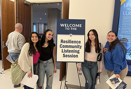 4 female students standing in front of a easel sign that says resillience community listening session