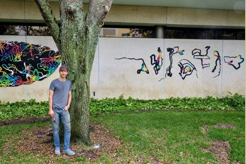 Kenny Jensen stands with his installation, Paths of Consumption: USFSP.