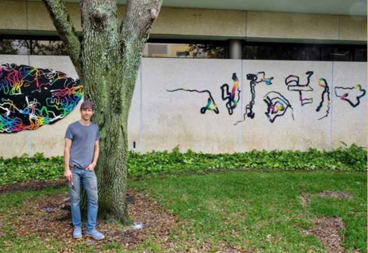 Kenny Jensen stands with his installation, Paths of Consumption: USFSP.