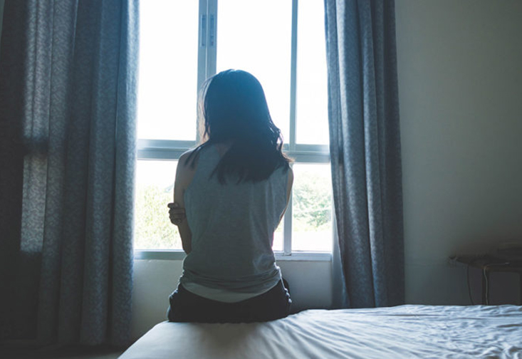 Women sitting on a bed looking out the window