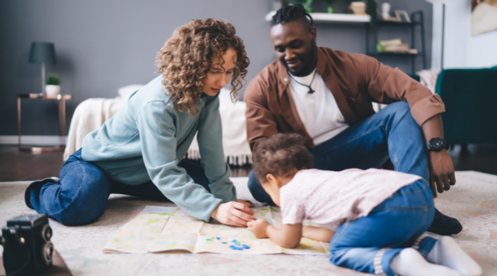 Two parents and a toddler doing a drawing activity in a living room