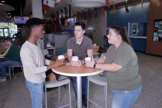 Three students drinking coffee at a table
