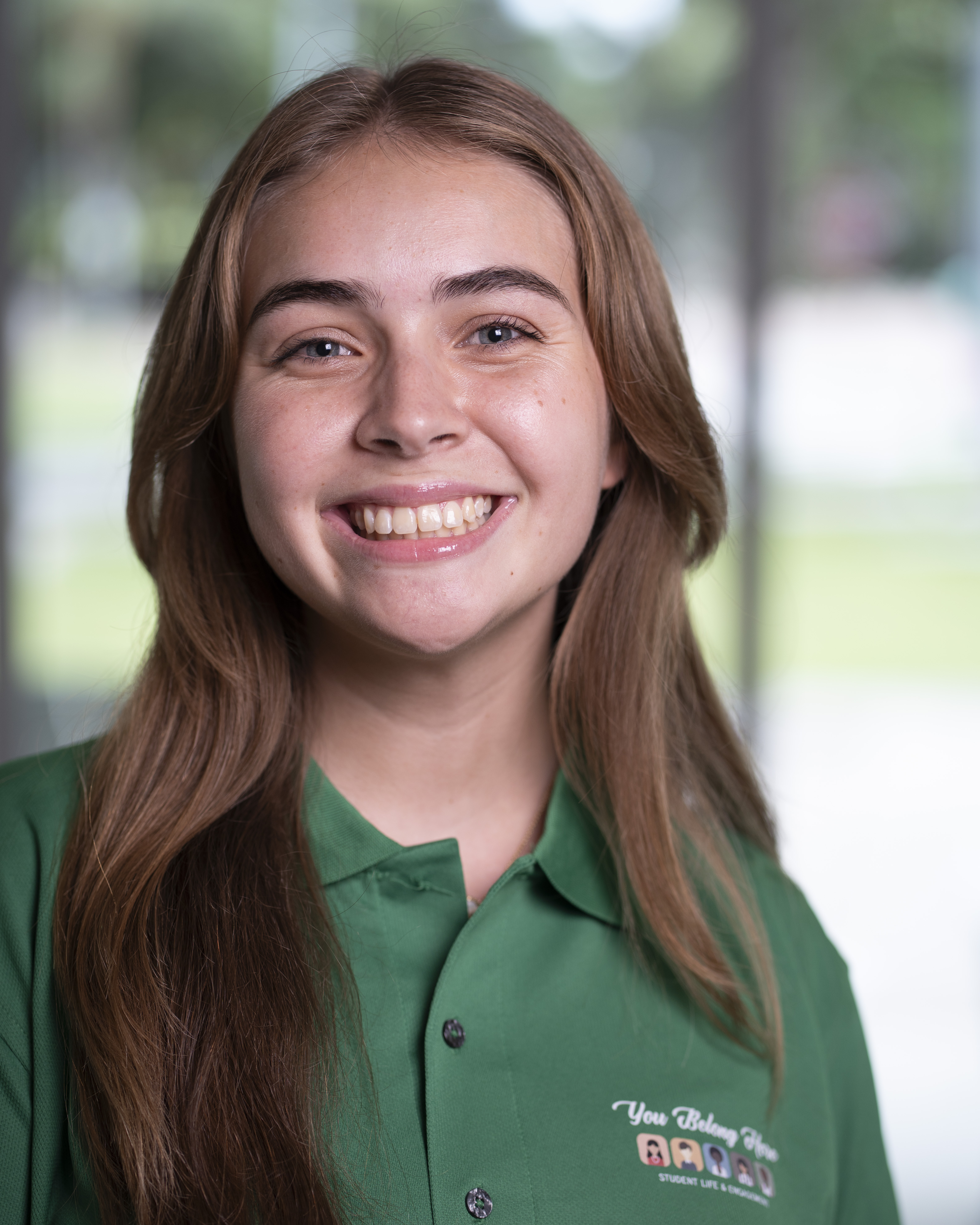 Woman in green polo smiles at camera.