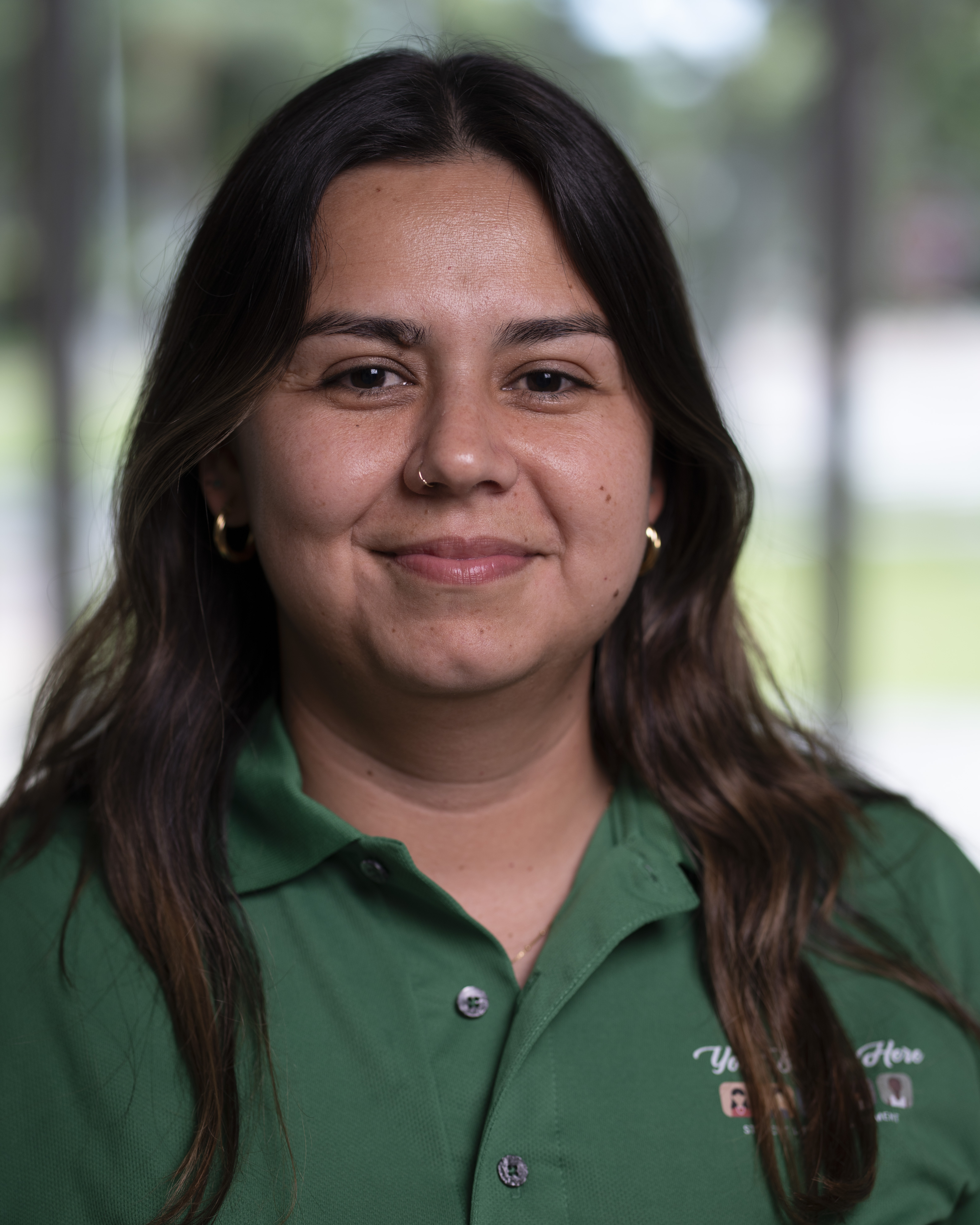 Woman in green polo smiles at camera.