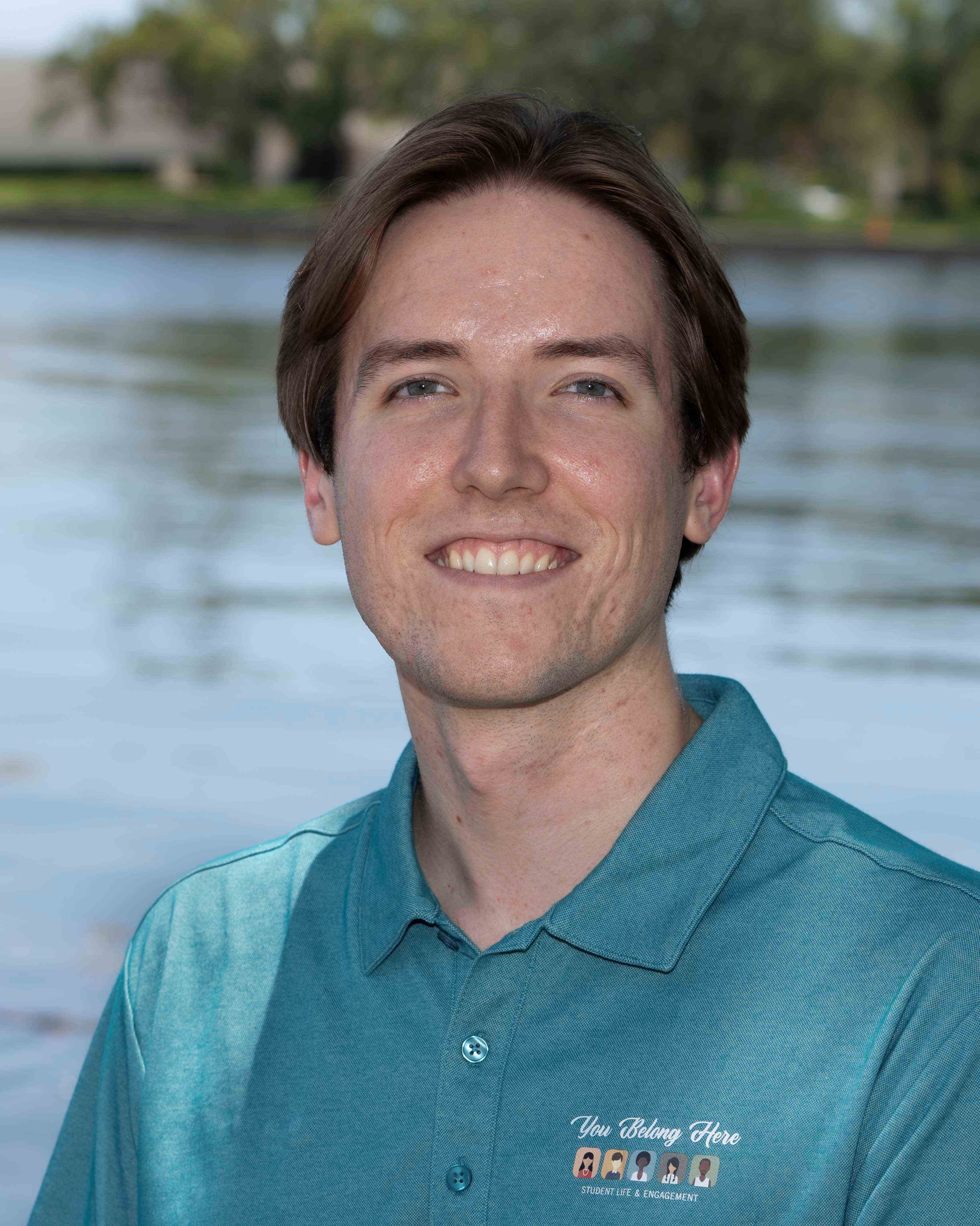 Jon Watson smiles in front of water in blue polo.