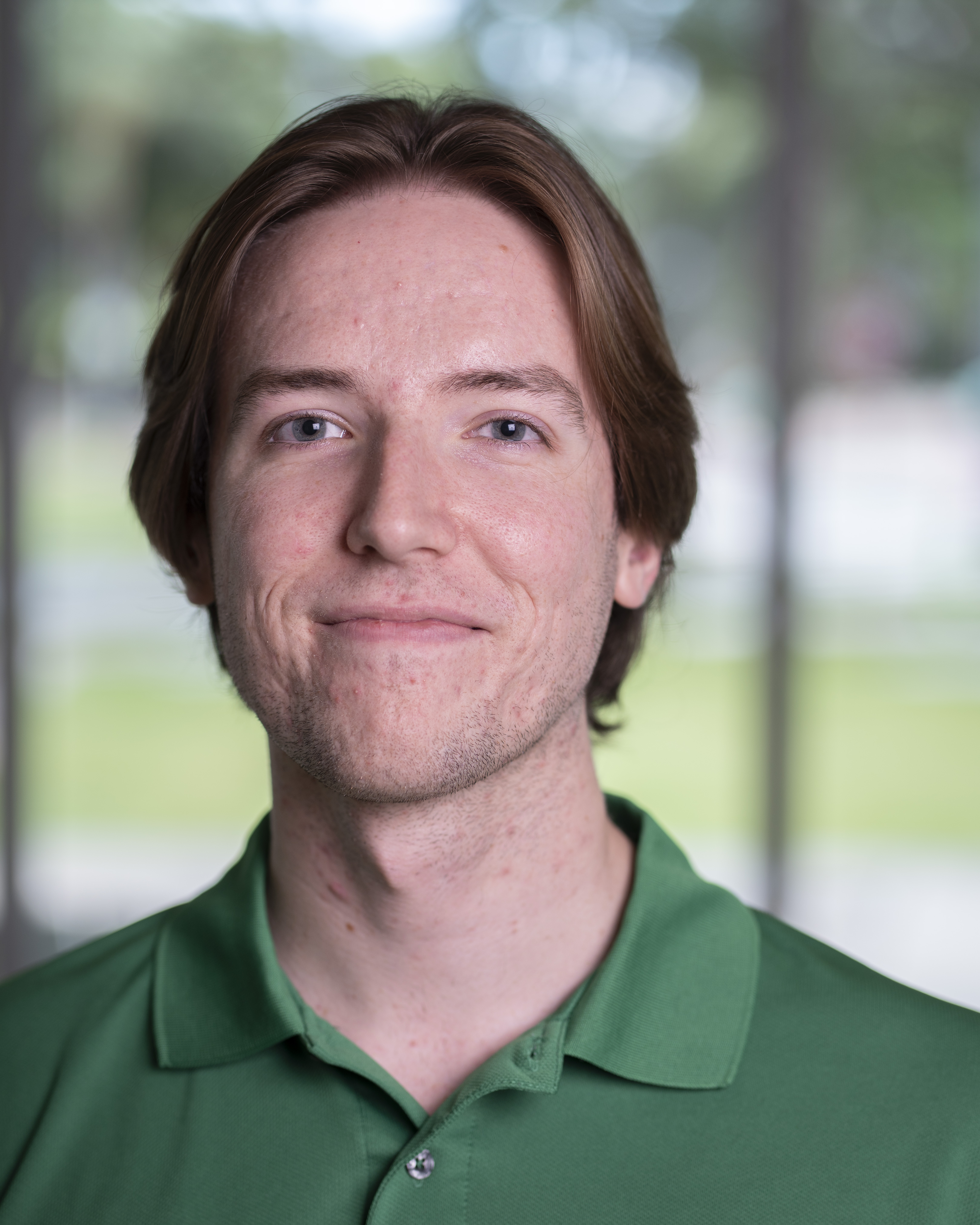 Man in a green polo smiles at the camera.