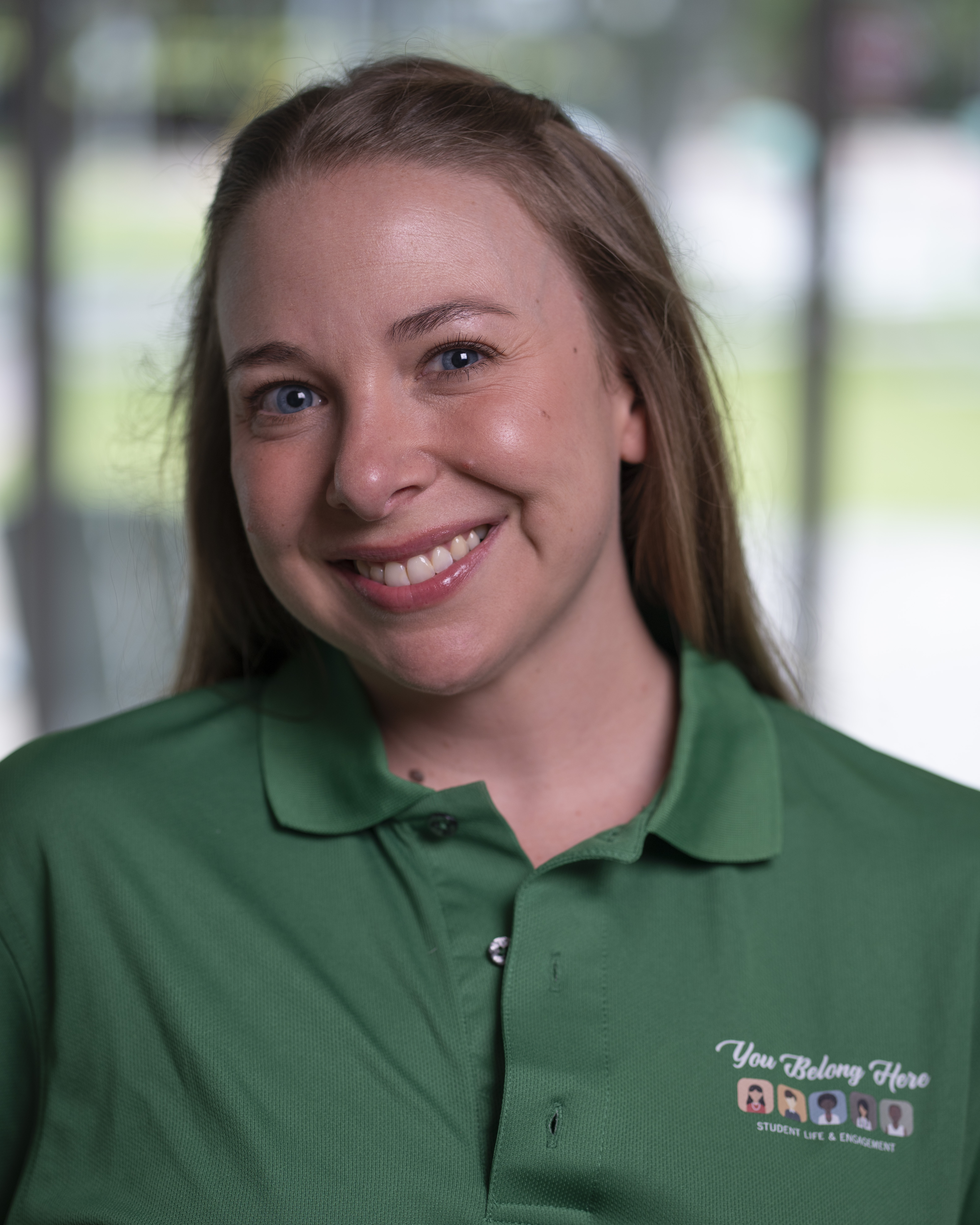 Woman in green polo smiles at camera.