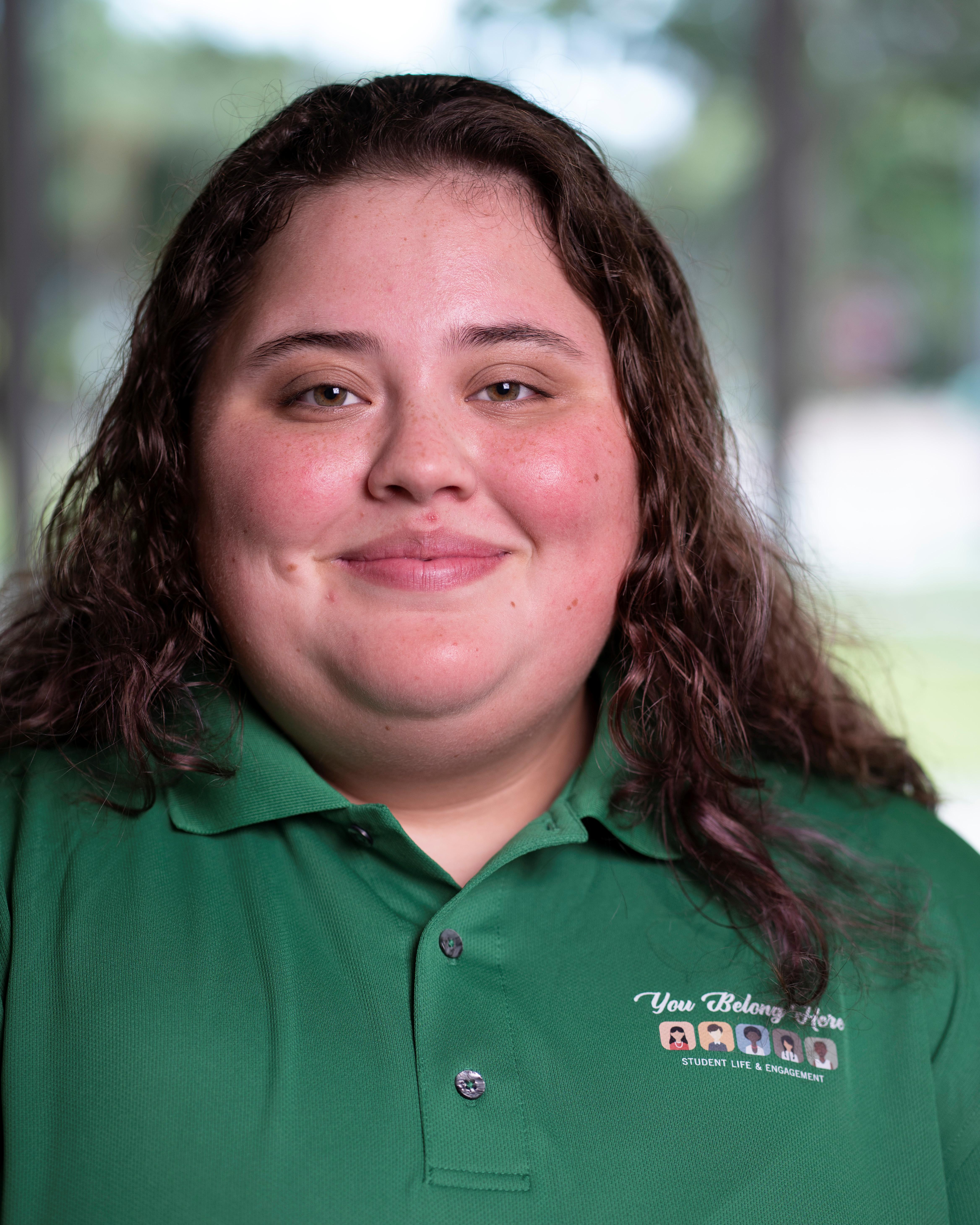 Woman in green polo smiles at camera.