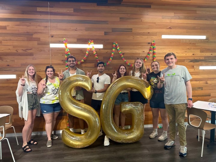 Students standing behind an SG sign