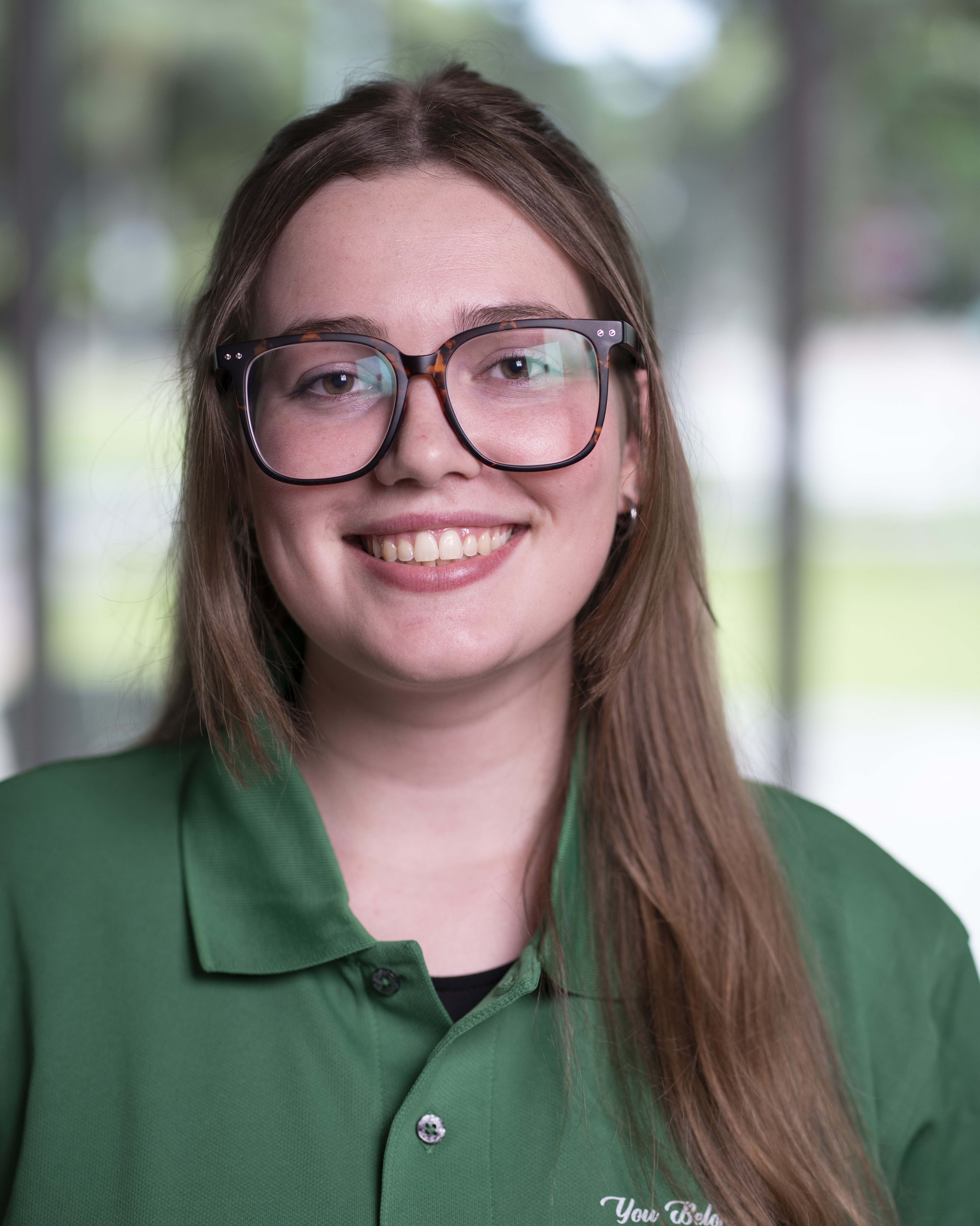 Woman in green polo smiles at camera.