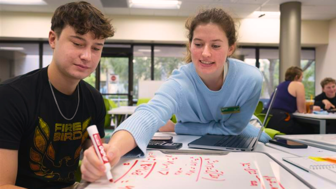 Peer tutor helps a student with a math problem using a whiteboard.  Visit the Student Success Center for free peer tutoring in DAV 107!